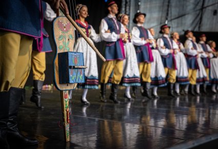 Zbliżenie na instrument kaszubski, w tle widoczni artyści w kostiumach kaszubskich