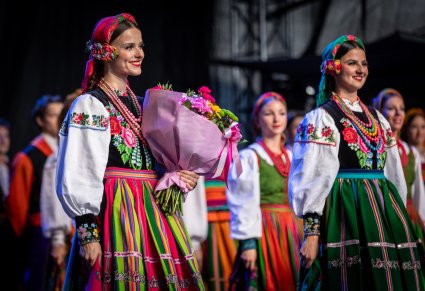 Zbliżenie na artystkę w kostiumie łowickim z kwiatami