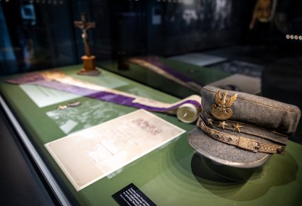 Zbliżenie na czapkę wojskową z 1920 roku wraz z innymi eksponatami umieszczonymi w gablocie