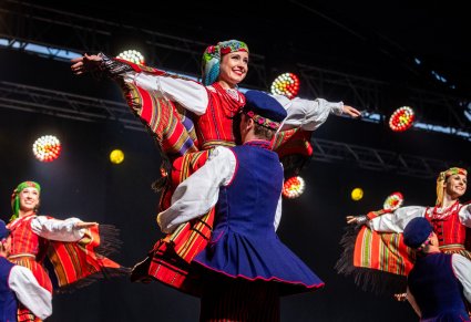 Zbliżenie na tancerkę w kostiumie sieradzkim podczas podnoszenia przez partnera