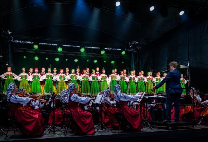 Chór w kostiumach kurpiowskich podczas występu wraz z orkiestrą