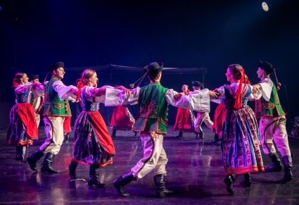 Grupa tancerzy w kostiumach spiskich na scenie