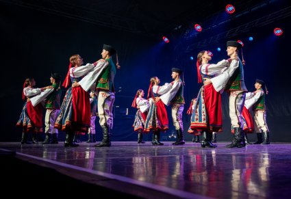 Grupa tancerzy w kostiumach spiskich na scenie