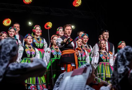 Zbliżenie na solistkę chóru podczas koncertu z widocznych chórem i orkiestrą