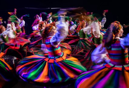 Grupa tancerek w kostiumach łowickich w obrotach na scenie