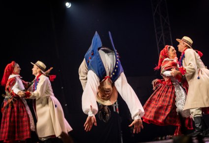 Artysta baletu w kostiumie krzemienickim robi fikołka na scenie