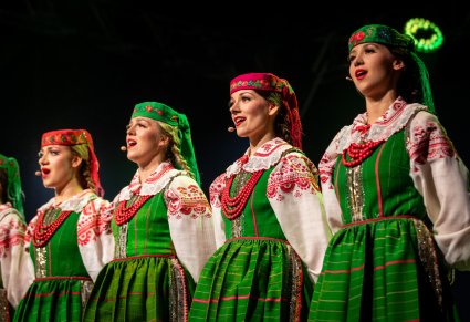 Zbliżenie na 4 chórzystki w kostiumach kurpii białych śpiewają na scenie