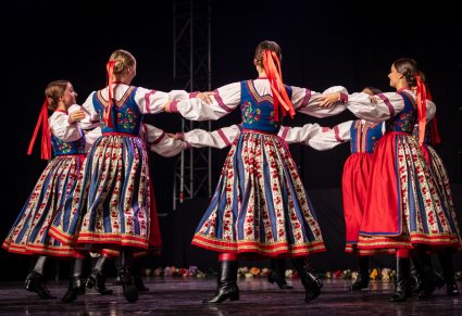 Artystki baletu w kostiumach spiskich tańczą w kółku na scenie