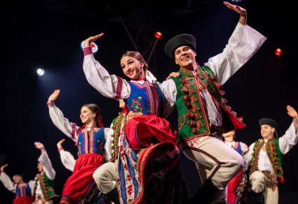 Artyści w kostiumach spiskich tańczą na scenie