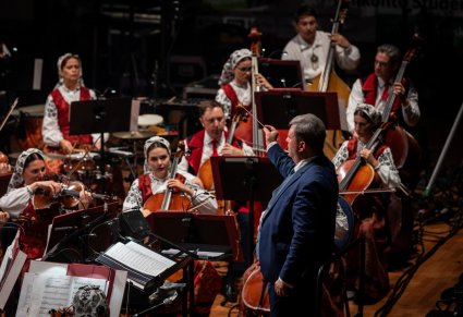 Orkiestra w kostiumach Wilanowskich - sekcja smyczkowa a przed nimi dyrygent