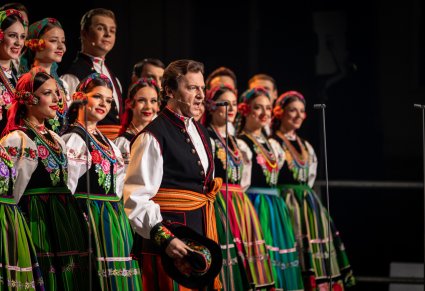 Solista w roli Furmana śpiewa a za nim stoi chór w kostiumach łowickich