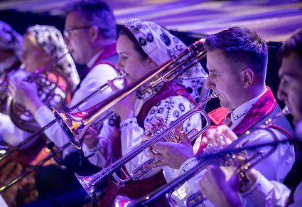 Zbliżenie na artystów orkiestry grających na trąbkach