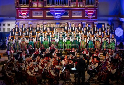 Chór Mazowsza w kostiumach łowickich a przed nimi orkiestra w kostiumach wilanowskich