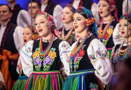 Zbliżenie na chórzystki w kostiumach łowickich śpiewające w duecie kolędę