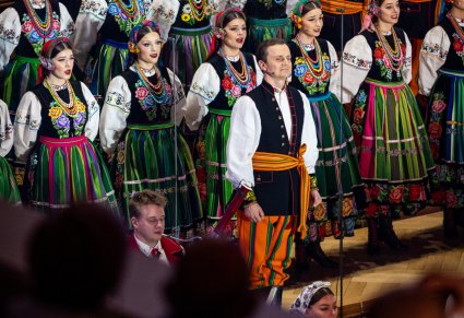 Widok z balkonu na śpiewającego solistę a w tle reszta chóru w kostiumach łowickich