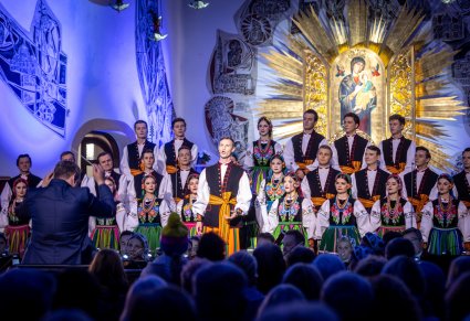 Solista chóru podczas występu na koncercie, w tle widoczny chór