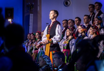 Solista chóru podczas występu na koncercie, w tle widoczny chór