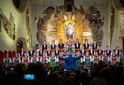 Chór i dyrygent podczas koncertu, widoczna widownia