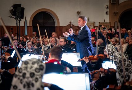 Zbliżenie na dyrygenta i orkiestrę podczas koncertu