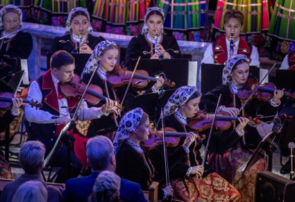 Zbliżenie na artystów orkiestry grających na skrzypcach podczas koncertu