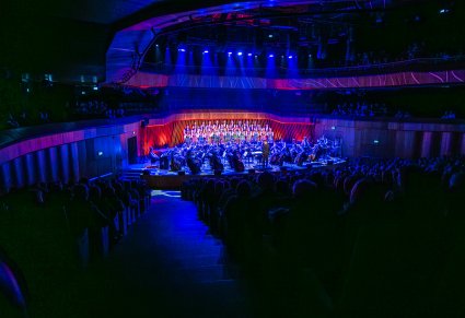 Wnętrze Cavatina Hall w Bielsku-Białej a w niej scena z Artystami Chóru w kostiumach łowickich i orkiestrą. Widoczna publiczność