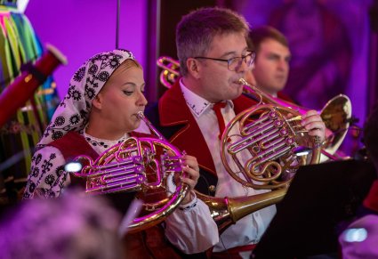 Zbliżenie na artystów orkiestry grających na waltorniach