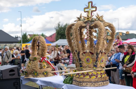  Zbliżenie na wieńce dożynkowe ustawione przed sceną koncertową, w tle publiczność