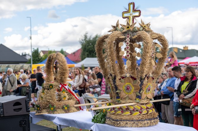  Zbliżenie na wieńce dożynkowe ustawione przed sceną koncertową, w tle publiczność