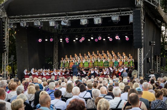  Na zdjęciu widoczny chór w kostiumie łowickim, wraz z orkiestrą i dyrygentem, a także fragment publiczności.