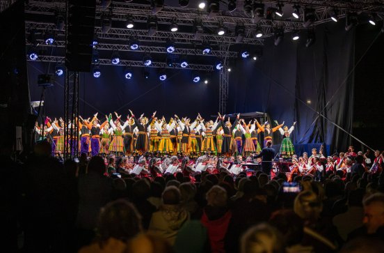  Widok z perspektywy publiczności na balet w kostiumach łowickich i sannickich,  a także na orkiestrę w kostiumach wilanowskich i podhalańskich, oraz dyrygenta