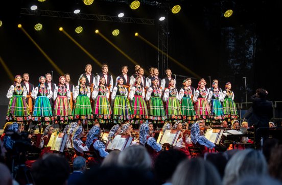  Artyści na scenie w kostiumach łowickich z widoczną orkiestrą
