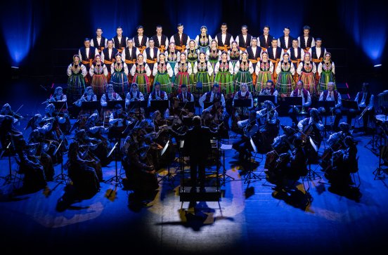  Na scenie Dyrektor Jacek Boniecki zwrócony w stronę Orkiestry i Artystów Chóru ubranych w kostiumy łowickie