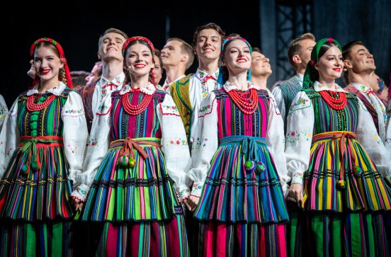  Zbliżenie na cztery Artystki w strojach opoczyńskich a za nimi Artyści również w strojach opoczyńskich